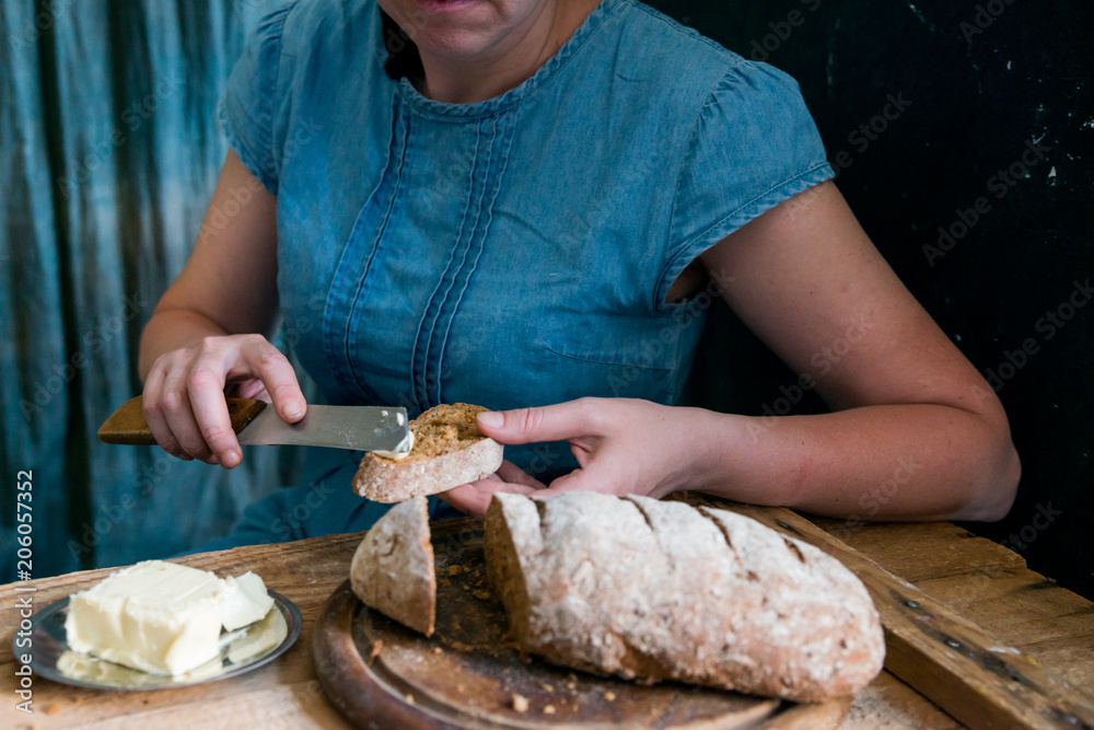 Woman puts butter on rye bread breakfast concept