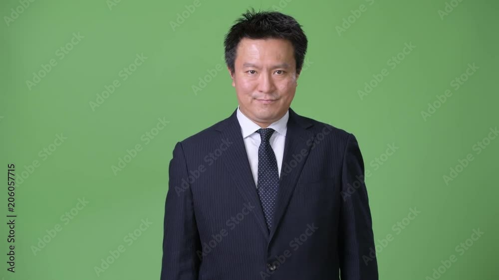 Mature Japanese businessman against green background Mature Japanese businessman against green background