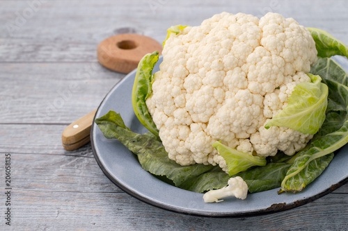 Fresh cauliflower on a round plate on an old wooden table. 