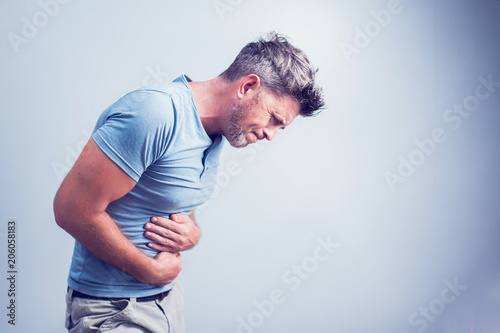 People, healthcare and health problem concept - unhappy man suffering from stomach ache over gray background