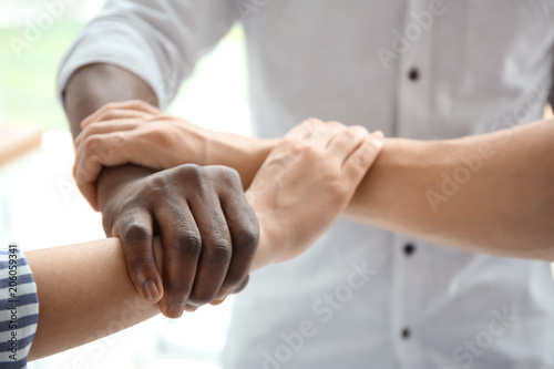 People holding hands on light background, closeup. Unity concept