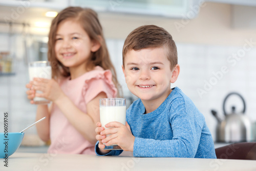 Cute little kids drinking milk in kitchen