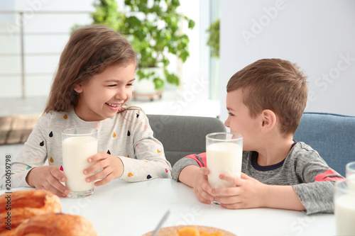 Cute little kids having breakfast with milk at table