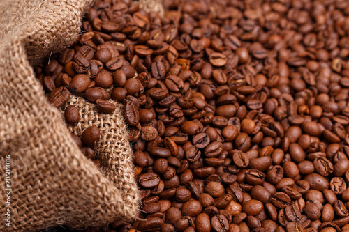 coffee beans in jute bag on wooden table. Burlap sack full of coffee beans on wood table