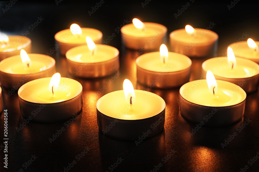 Wax candles burning on table in darkness, closeup Wax candles burning on table in darkness, closeup