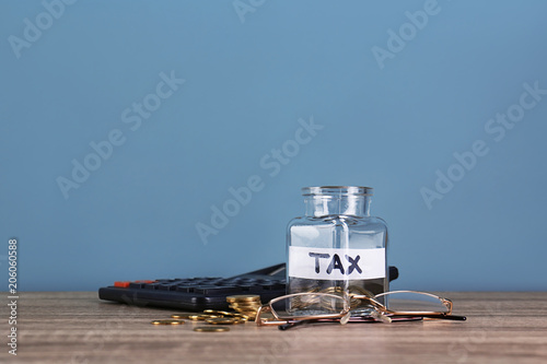 Glass jar with label "TAX" and coins on table