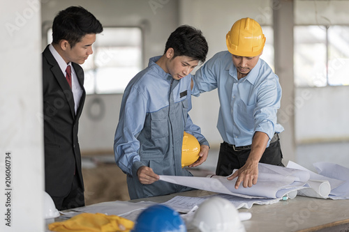 Architect with businessman and engineer are planning on blueprint. Architect is pointing on the blueprint.