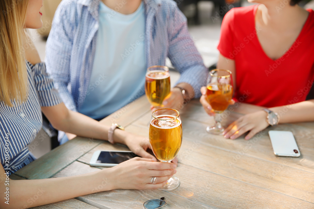 Young people with glasses of cold beer at table Young people with glasses of cold beer at table