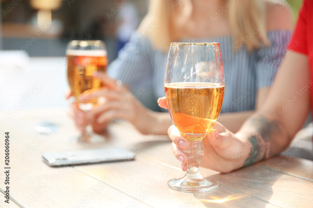 Young women with glasses of cold beer at table Young women with glasses of cold beer at table