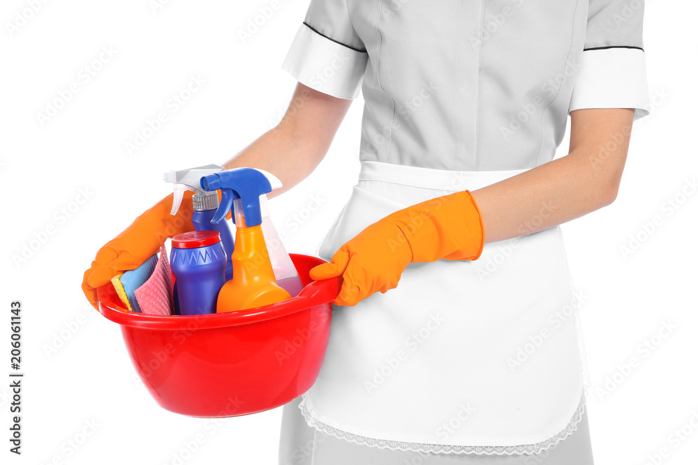 Young chambermaid holding basin with cleaning supplies on white background Young chambermaid holding basin with cleaning supplies on white background