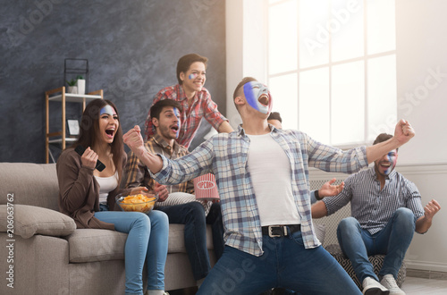 Happy sport fans with colored faces at home photo