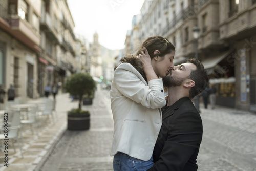 Man kissing woman in the street while carrying her embracing