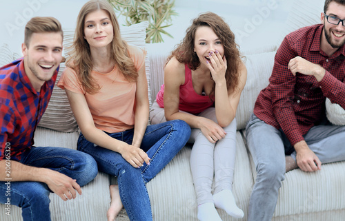 group of cheerful friends watching videos, sitting on the couch