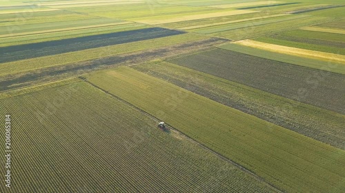 Tractor cultivating corn crop field, aerial view from drone pov photo