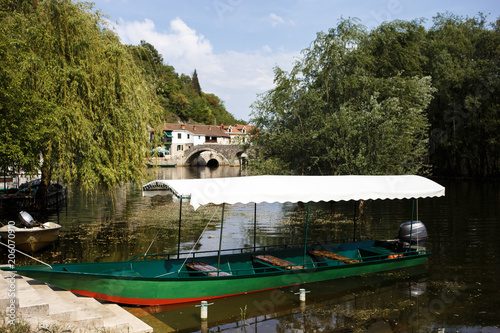 a boat wwith tent on the river with trees and bridge in background photo