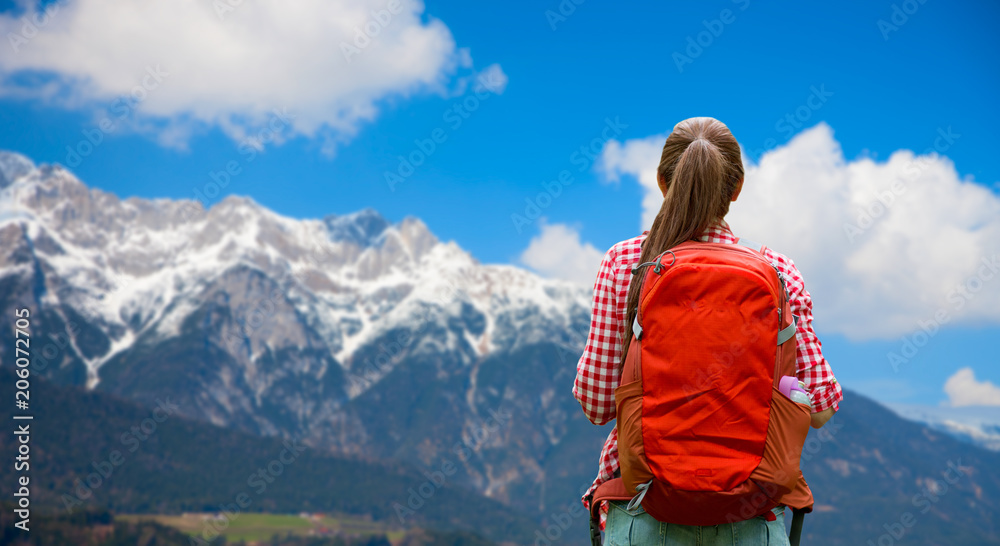 travel, tourism and hike concept - young woman with backpack over alps mountains background