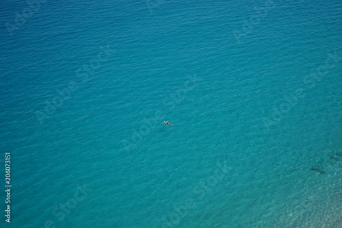 Blick aus der Vogelperspektive auf eine schwimmende Person im Mittelmeer am Strand von Tropea