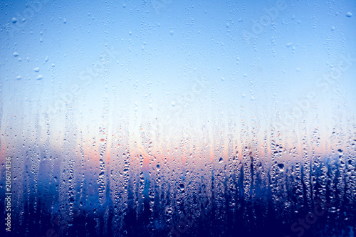 Clear water drops on the surface of the glass window. Color transition .Light blue, white, pink, dark blue shades. Perfect background for the artistic collages and illustrations.
