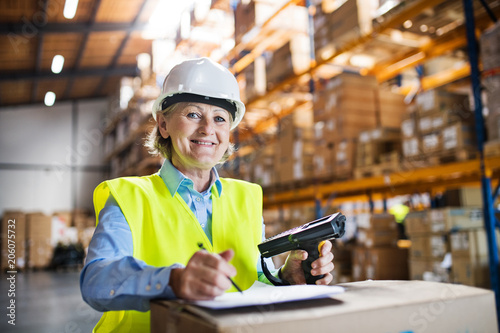 Senior warehouse woman worker with barcode scanner.
