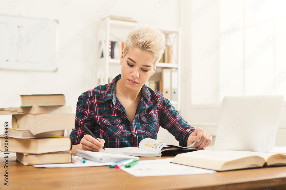 Student girl studying at table full of books Student girl studying at table full of books