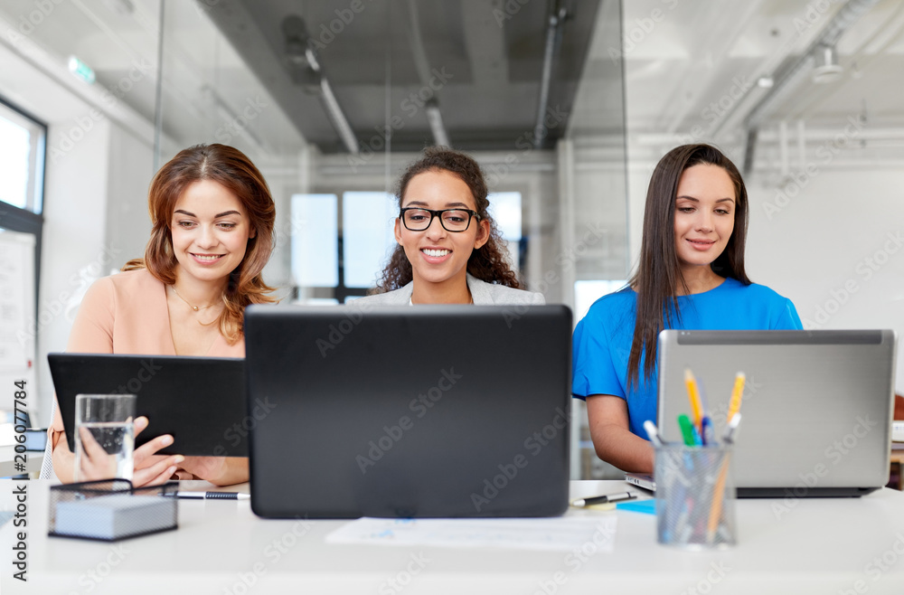 business, teamwork and people concept - female team or businesswomen with tablet pc and laptop computers working at office business, teamwork and people concept - female team or businesswomen with tablet pc and laptop computers working at office