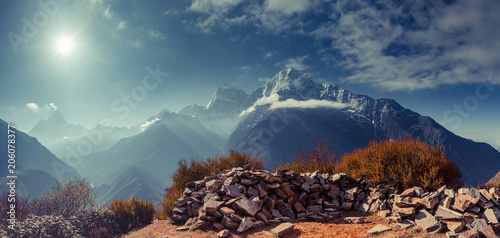 The gorgeous scene the boulders on the mighty misty snow-covered mountain background. The Himalayas. Everest Base Camp trek in the Sagarmatha National Park in the north-eastern Nepal. © Goinyk
