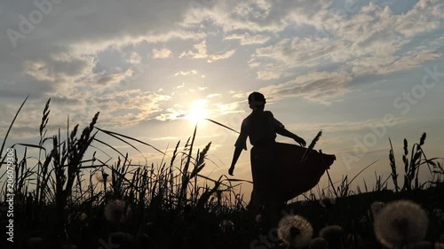 Dancing female silhouette on dandelion field