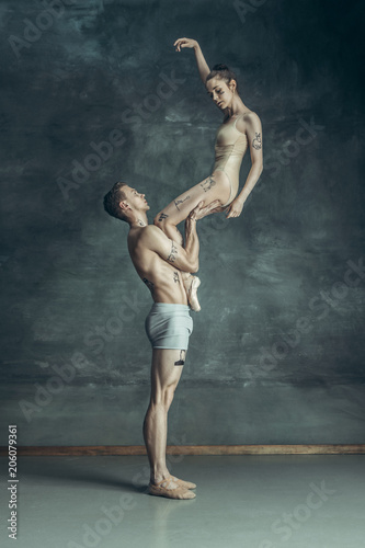 Fototapeta Naklejka Na Ścianę i Meble -  The young modern ballet dancers posing on gray studio background