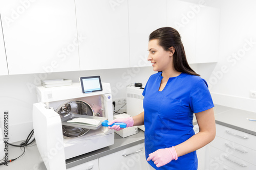 dentistry  medicine and healthcare concept - female dentist assistant arranging sterilization or disinfection of tools at dental clinic