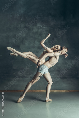 Fototapeta Naklejka Na Ścianę i Meble -  The young modern ballet dancers posing on gray studio background