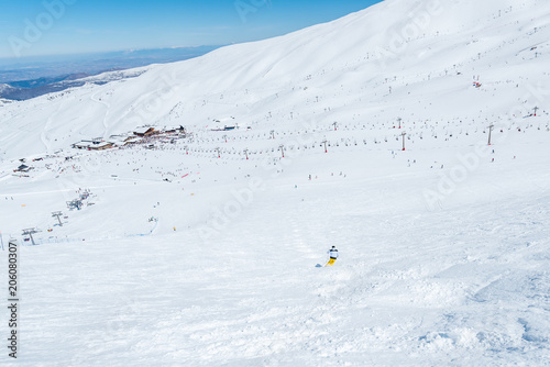 Ground view of Sierra Nevada mountain resort pistes with a skier going downhill and off-piste, from 
