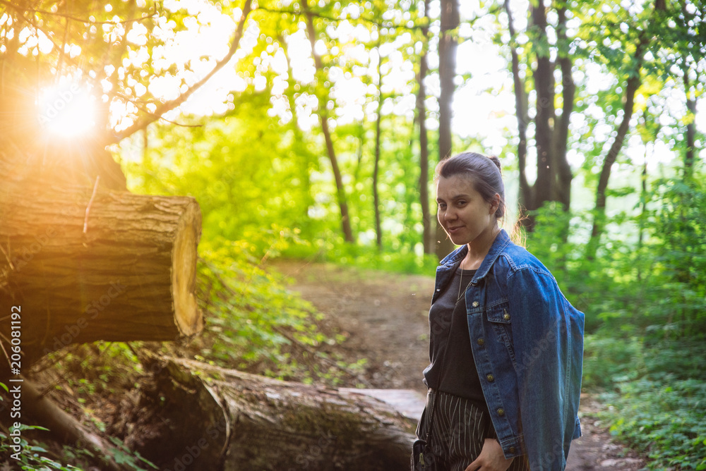 Fototapeta premium young adult woman posing at forest trail on sunset