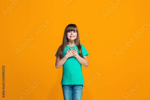 Beautiful teen girl looking suprised isolated on orange