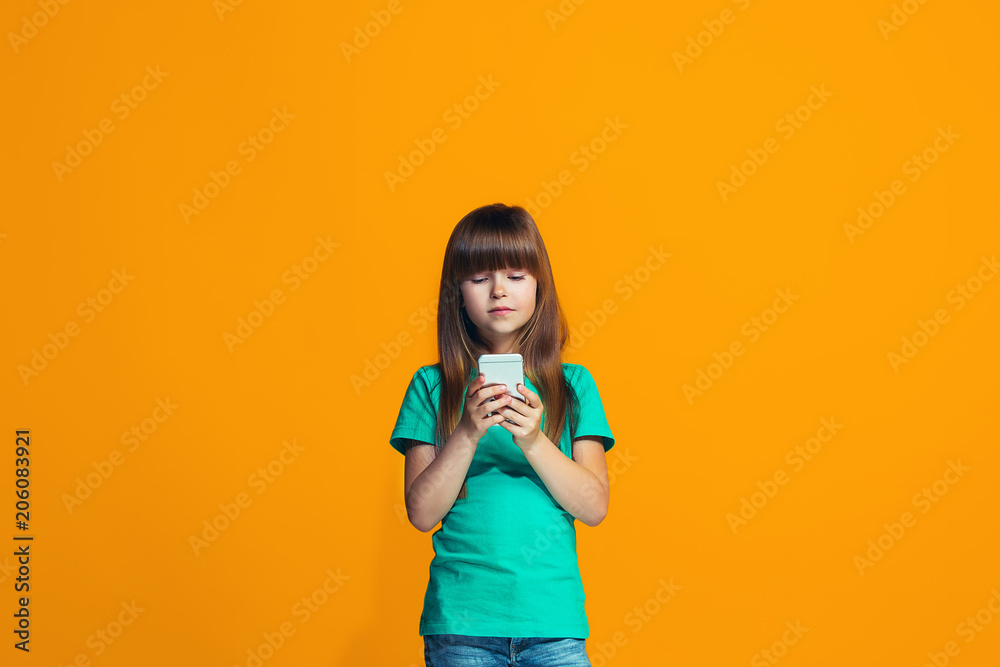 The happy teen girl standing and smiling against orange background. The happy teen girl standing and smiling against orange background.