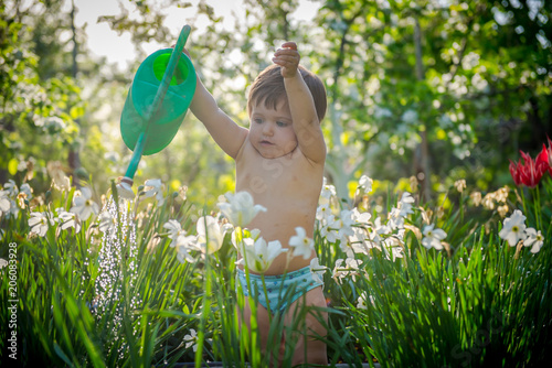 girl watering flowers. sweet girl helps gardening. Background of the summer garden 