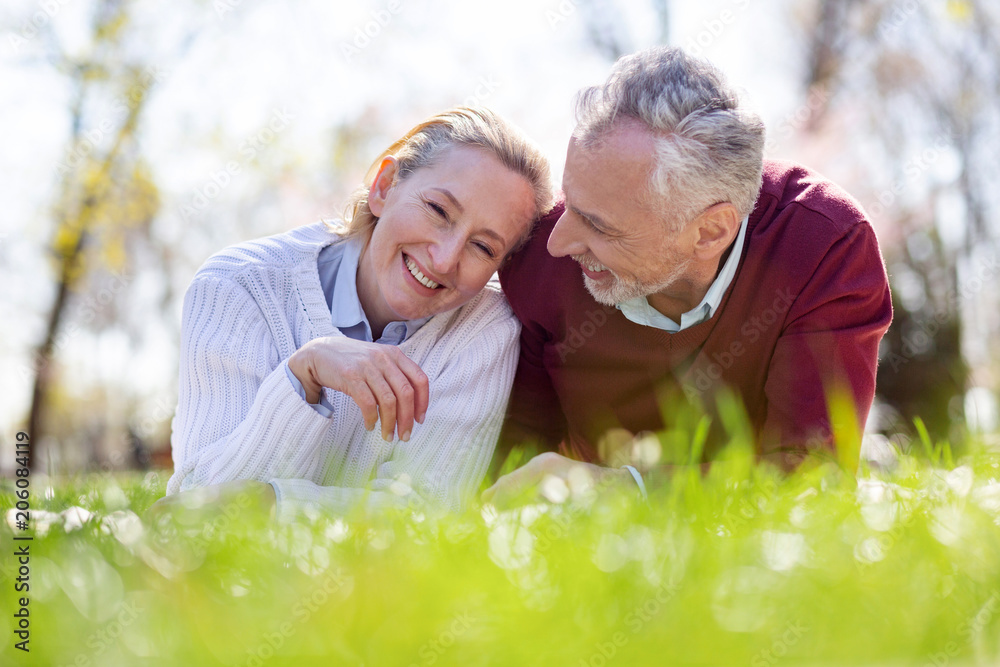 Wonderful mood. Happy joyful couple laughing while lying in the grass together Wonderful mood. Happy joyful couple laughing while lying in the grass together