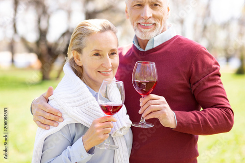 Pleasant drink. Joyful positive couple drinking wine while having a romantic picnic