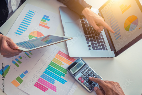 Men working on analysis financial documents on a laptop, digital tablet and calculator