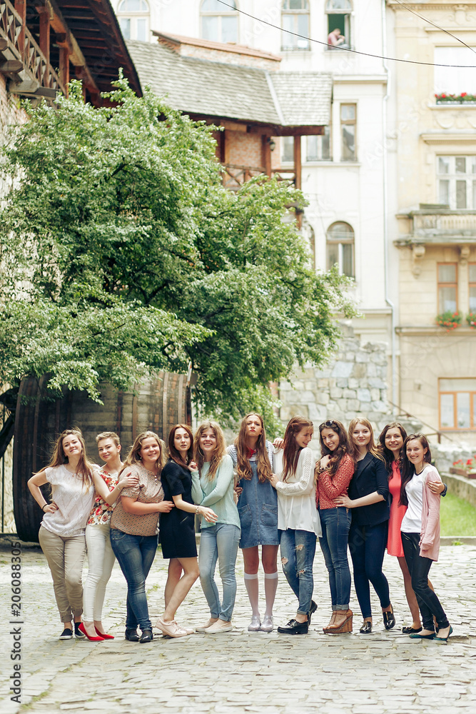 Fototapeta premium Group of happy stylish women posing on background of old european city street, travel or celebrating friendship concept, moments of happiness