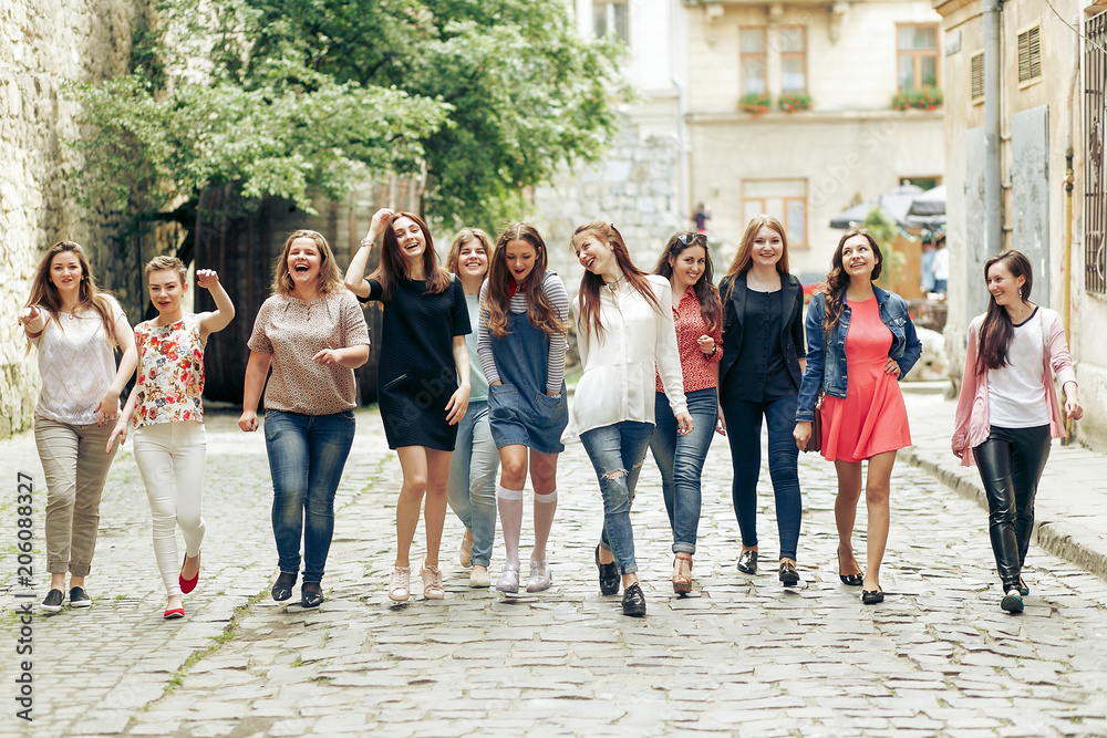 Fototapeta premium Group of many happy women walking having fun on background of old european city street, celebrating friendship concept, moments of happiness