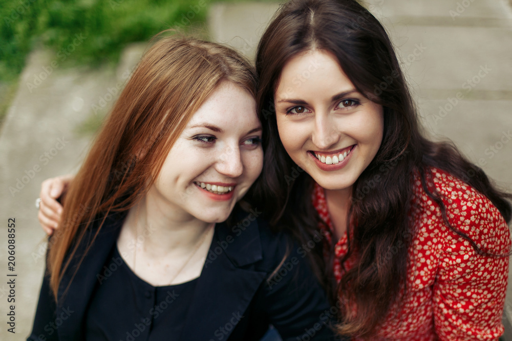 Fototapeta premium two stylish happy woman hugging in europe city park, sincere moments friendship concept