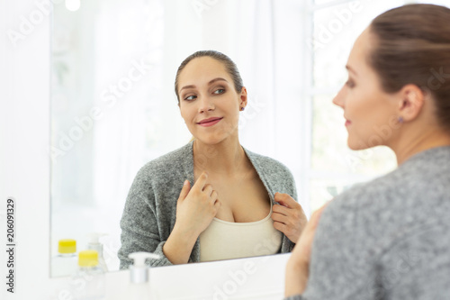 Gorgeous decollate. Satisfied glad woman gazing at mirror and smiling