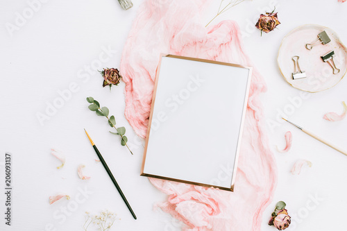Creative wedding composition with photo frame mock up, pink blanket, flowers, eucalyptus branches and brushes on white background. Flat lay, top view stylish art concept.