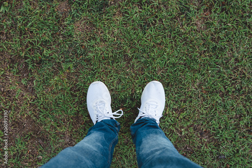 Man wears jeans and white sneaker shoes standing on grass. © AePatt Journey