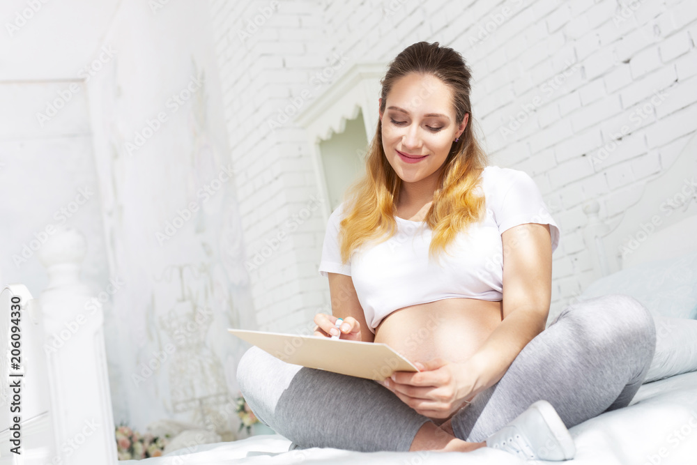 Happy mother. Low angle of happy pregnant woman carrying pregnancy journal and sitting Happy mother. Low angle of happy pregnant woman carrying pregnancy journal and sitting