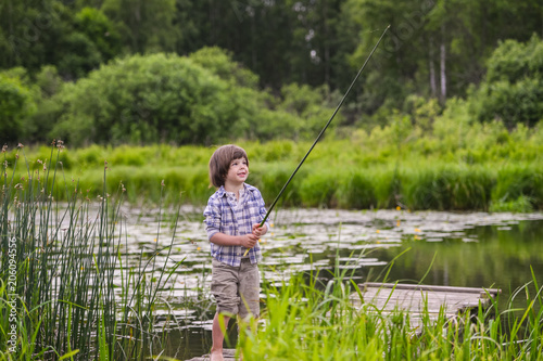 barefoot boy on a wooden bridge on the river. Considering to pull the plant