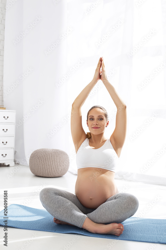 Body reserves. Beautiful pregnant woman staring at camera and practicing yoga