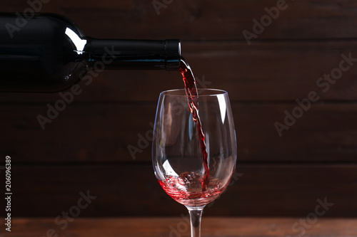Pouring delicious red wine into glass on blurred background