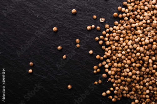 coriander seeds on a dark stone background, essential oil