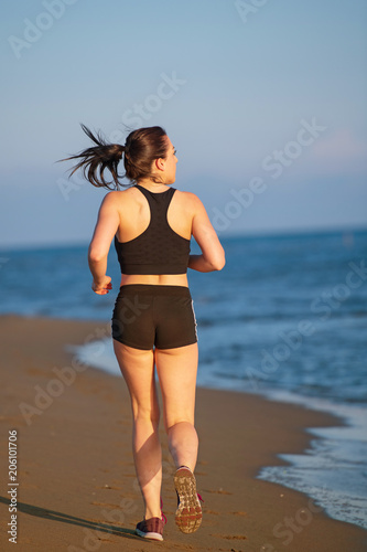 Fototapeta Naklejka Na Ścianę i Meble -  Healthy young fitness woman runner running on sunrise seaside trail